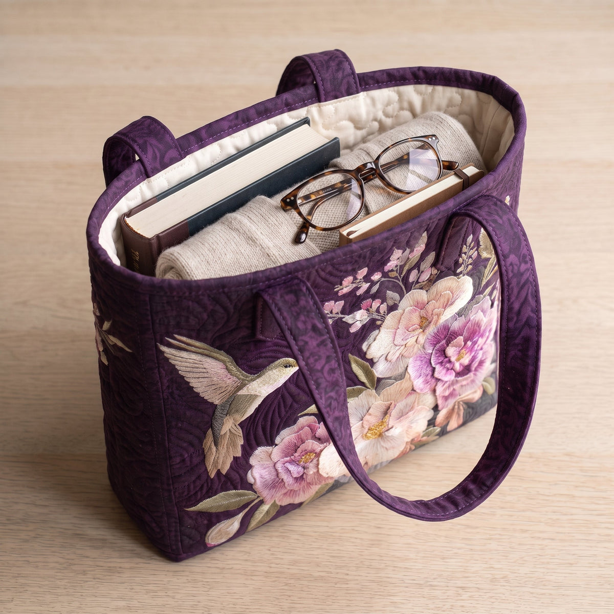 Artisanal Quilted Bag - Hummingbirds and Orchids — packed with a hardback book, a folded cardigan and reading glasses