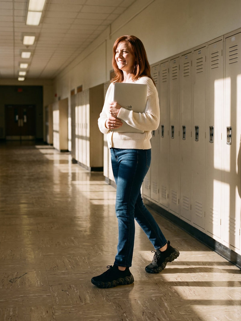 A teacher walking a school hallway wearing Again Walk